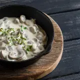 Cremige Champignon Rahmsauce in einer Gusseisenpfanne, garniert mit frischem Thymian.