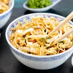 Ein Schüsselchen mit friss dich dumm salat, Nudeln, Gemüse und Erdnüssen, bereit zum Genießen mit Stäbchen.