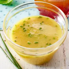 Ein Glas mit cremigem honig senf dressing, garniert mit Schnittlauch. Perfekt für einen frischen Salat.
