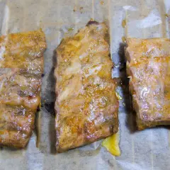 Drei saftige spareribs sous vide, mariniert und auf Backpapier liegend, bereit zum Genuss.