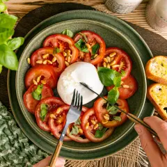 Frischer Burrata mit Tomaten, Pinienkernen und Basilikum, perfekt für leichte Burrata Rezepte. Dazu geröstetes Brot.