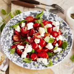 Frischer tomatensalat mit feta, garniert mit Basilikum. Dazu gibt es knuspriges Brot.