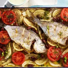 Zwei goldbrassen im backofen mit Tomaten, Fenchel und Oliven, appetitlich zubereitet.