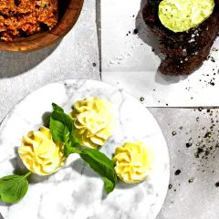 Knoblauchbutter rezept: Ein Steak mit Kräuterbutter, dazu Kartoffelröschen und eine Schüssel mit würziger Butter.