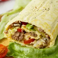 Herzhafte Big Mac Rolle gefüllt mit Hackfleisch, Salat, Tomaten und Käse, serviert auf knackigem Salatblatt.