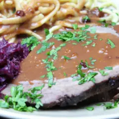 Saftiger Sauerbraten, eingelegt und serviert mit Spätzle und Rotkohl. Ein Klassiker, der auf der Zunge zergeht.