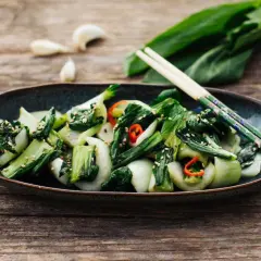 Ein Teller mit gebratenem Pak Choi, bestreut mit Sesam und Chili. Perfekt für einfache Pak Choi Rezepte.