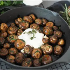 Gebratene Champignons mit Kräutern und cremiger Sauce in einer Gusseisenpfanne. Perfekt für leckere Champignons Rezepte.