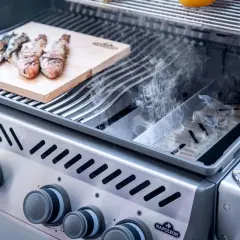 Fisch auf Holzbrett im Gasgrill, Rauch steigt auf. Leckeres Smoken im Gasgrill für ein besonderes Aroma.
