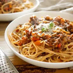 Herzhafte vegetarische Bolognese mit Linsen und Spaghetti, garniert mit Parmesan und Basilikum.