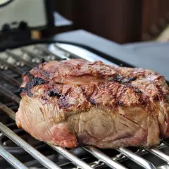 Ein saftiges Steak brutzelt auf einem Elektrogrill. Die Grillstreifen sind deutlich sichtbar, und das Fleisch ist perfekt gebräunt.