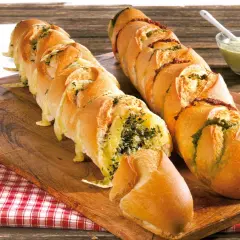 Zwei knusprige Baguettes zum Grillen, gefüllt mit Kräutern und Käse, daneben eine Schale Dip.