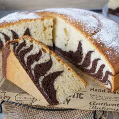Ein saftiger Zebrakuchen, perfekt für das Zebrakuchen Rezept. Mit Puderzucker bestäubt und einem Stück zum Probieren.