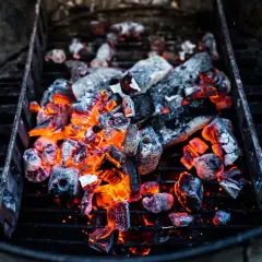 Glühende Kohlen im Grill, bereit für das perfekte Barbecue. Die Frage "wie viel Kohle zum Grillen" stellt sich hier nicht, denn diese Menge verspricht Hitze und Genuss.
