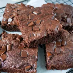 Saftige Zucchini Brownies mit Schokostückchen, auf einem Gitterrost arrangiert.