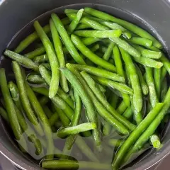 Grüne Bohnen kochen in einem Topf mit Wasser. Sie sind frisch und leuchtend grün, bereit für eine gesunde Mahlzeit.