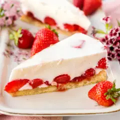 Ein Stück Erdbeerkuchen mit weißer Creme und frischen Erdbeeren auf einem Teller.