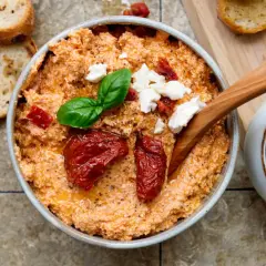 Cremiger Feta-Dip mit getrockneten Tomaten, Basilikum und Brot.