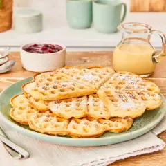 Leckere Waffeln ohne Ei, bestäubt mit Puderzucker, serviert mit Marmelade und Vanillesauce. Ein Genuss für jeden Tag!