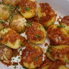 Knusprige parmesan kartoffeln mit Kräutern und grobem Salz bestreut, in einer weißen Auflaufform.