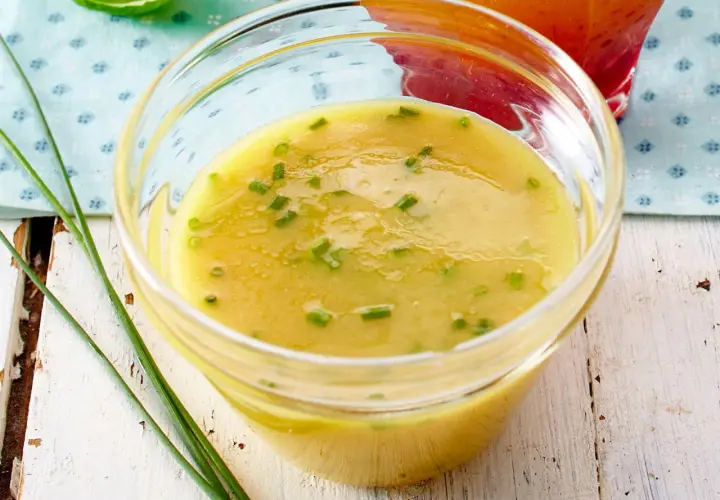 Ein Glas mit cremigem honig senf dressing, garniert mit Schnittlauch. Perfekt für einen frischen Salat.