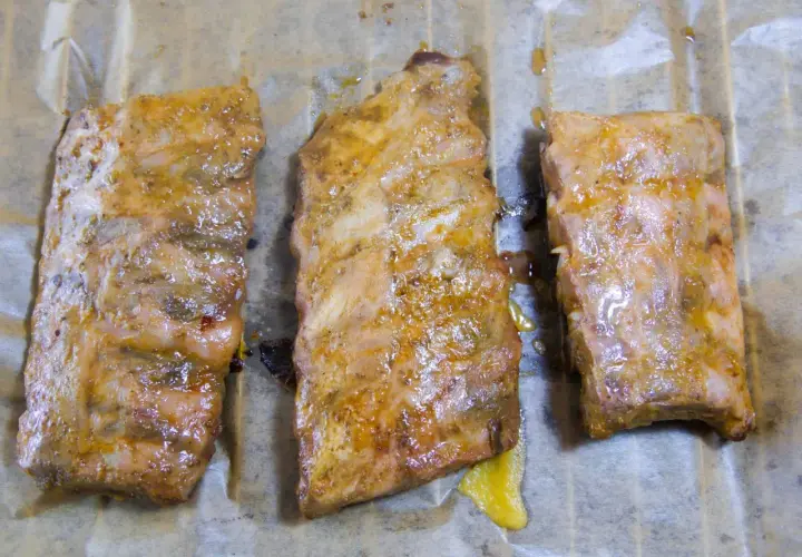 Drei saftige spareribs sous vide, mariniert und auf Backpapier liegend, bereit zum Genuss.