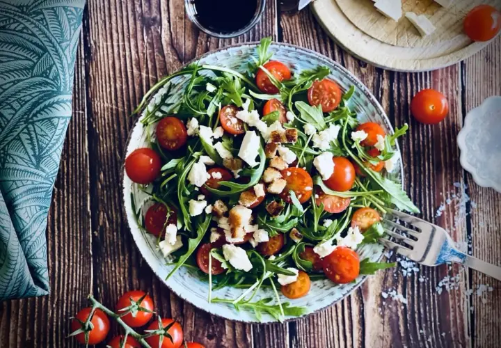Frischer Rucola Salat mit Kirschtomaten und Feta, garniert mit Croutons. Ein leichter Genuss!