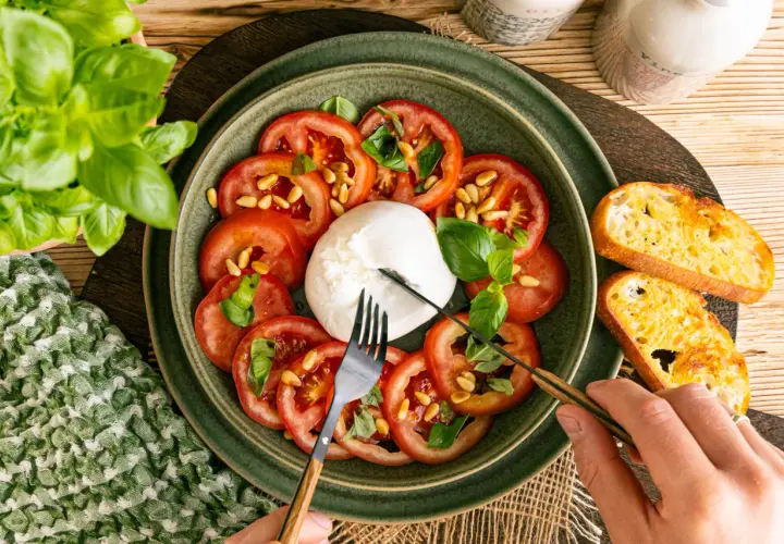 Frischer Burrata mit Tomaten, Pinienkernen und Basilikum, perfekt für leichte Burrata Rezepte. Dazu geröstetes Brot.