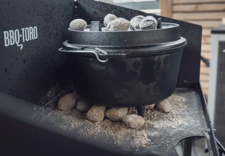 Ein Dutch Oven auf einem Gasgrill, bereit für ein köstliches Outdoor-Abenteuer. Glühende Kohlen sorgen für die perfekte Hitze.
