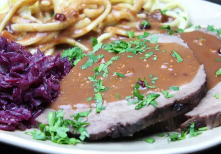 Saftiger Sauerbraten, eingelegt und serviert mit Spätzle und Rotkohl. Ein Klassiker, der auf der Zunge zergeht.