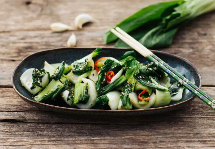 Ein Teller mit gebratenem Pak Choi, bestreut mit Sesam und Chili. Perfekt für einfache Pak Choi Rezepte.