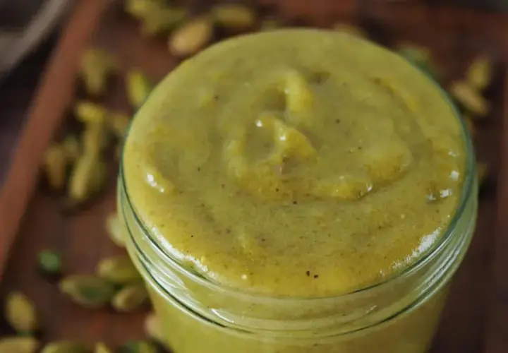 Selbstgemachte Pistaziencreme in einem Glas, umgeben von ganzen Pistazien. Perfekt zum Backen und Genießen.