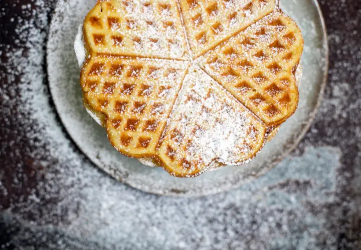Herzförmige Waffeln, bestäubt mit Puderzucker, ein köstliches Rezept für süße Momente.