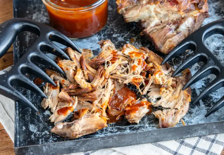 Zartes pulled pork sous vide, mit BBQ-Sauce beträufelt, bereit zum Zerreißen mit Fleischgabeln.