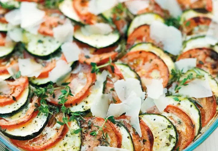 Schicht für Schicht ein Genuss: Ein köstlicher Tomaten Zucchini Auflauf, garniert mit Parmesan und frischen Kräutern.