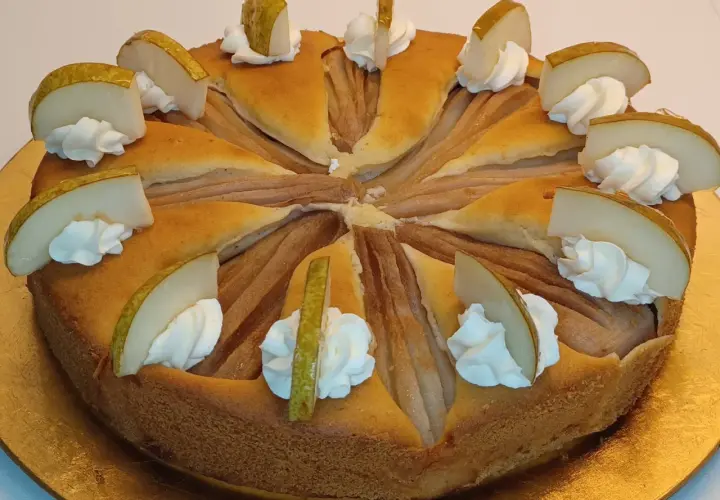 Ein köstlicher Birnenkuchen, verziert mit Sahnetupfern und frischen Birnenspalten. Perfekt für ein Birnenkuchen Rezept.