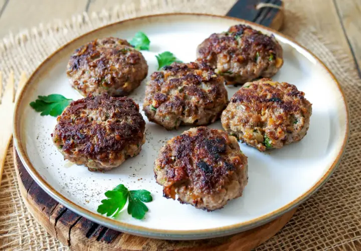 Sechs goldbraune Buletten, frisch gebraten, liegen auf einem Teller. Ein einfaches, aber köstliches Buletten Rezept.