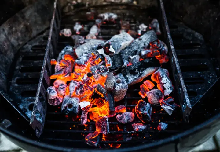 Glühende Kohlen im Grill, bereit für das perfekte Barbecue. Die Frage "wie viel Kohle zum Grillen" stellt sich hier nicht, denn diese Menge verspricht Hitze und Genuss.