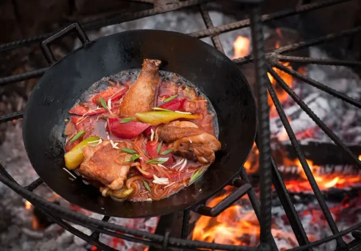 Hähnchen mit Gemüse in einer Pfanne über offenem Feuer. Tolle Camping Essen Ideen für ein herzhaftes Mahl.