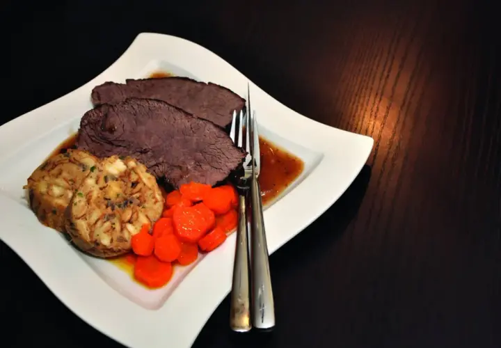 Saftiger Rinderbraten im Dutch Oven, serviert mit Klößen und Karotten. Ein Klassiker, der auf der Zunge zergeht.