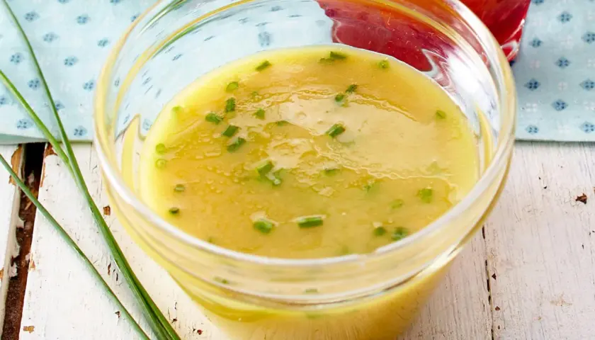Ein Glas mit cremigem honig senf dressing, garniert mit Schnittlauch. Perfekt für einen frischen Salat.