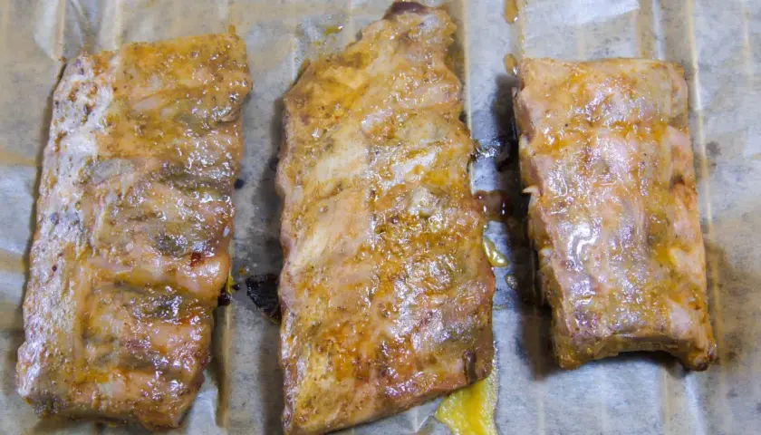 Drei saftige spareribs sous vide, mariniert und auf Backpapier liegend, bereit zum Genuss.