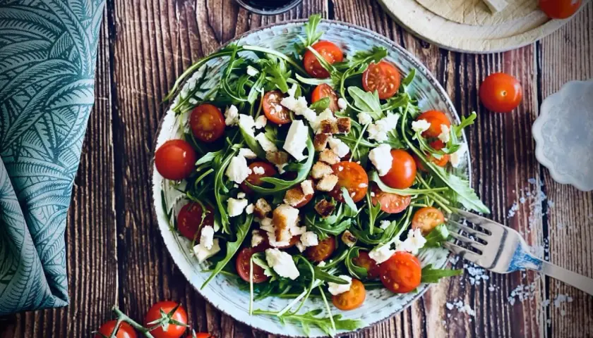 Frischer Rucola Salat mit Kirschtomaten und Feta, garniert mit Croutons. Ein leichter Genuss!