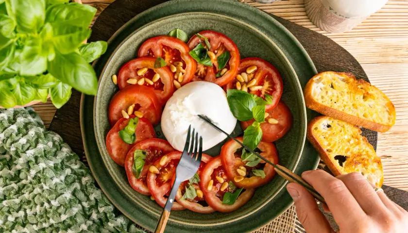 Frischer Burrata mit Tomaten, Pinienkernen und Basilikum, perfekt für leichte Burrata Rezepte. Dazu geröstetes Brot.