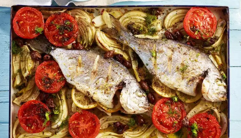 Zwei goldbrassen im backofen mit Tomaten, Fenchel und Oliven, appetitlich zubereitet.