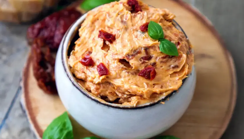 Cremige Tomatenbutter, garniert mit Basilikum und getrockneten Tomatenstücken. Ein köstliches Rezept für Tomatenbutter, perfekt zum Dippen oder Bestreichen.