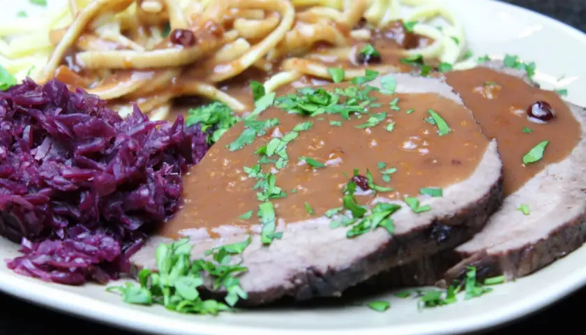 Saftiger Sauerbraten, eingelegt und serviert mit Spätzle und Rotkohl. Ein Klassiker, der auf der Zunge zergeht.