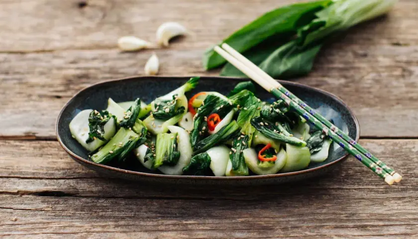 Ein Teller mit gebratenem Pak Choi, bestreut mit Sesam und Chili. Perfekt für einfache Pak Choi Rezepte.