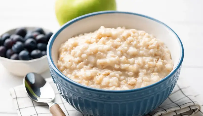 Herzhaftes Porridge-Rezept mit Blaubeeren und Apfel. Ein Löffel wartet auf den Genuss.