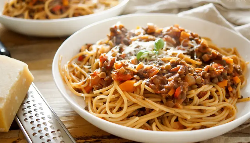 Herzhafte vegetarische Bolognese mit Linsen und Spaghetti, garniert mit Parmesan und Basilikum.